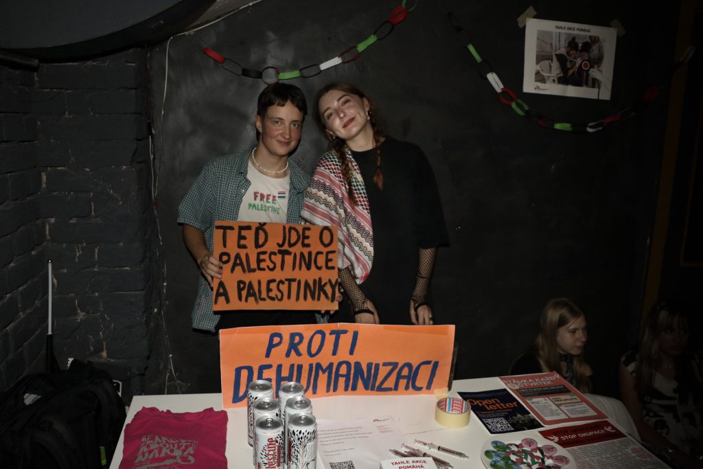 Dva lidé u stánku s cedulemi: Teď jde o palestince a palestinky a Proti dehumanizaci